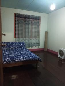 een slaapkamer met een bed en een raam met een gordijn bij Camp Jenil Serenity Homestay in Malabuñgan