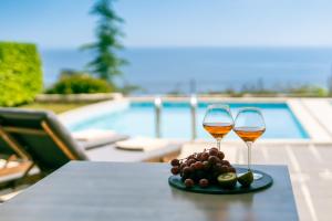 two glasses of wine on a table next to a pool at Sivota Diamond Spa Resort in Syvota