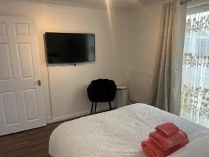 a bedroom with a bed and a flat screen tv at Corby Guest House in Corby