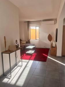 sala de estar con mesa y alfombra roja en Maison à 800m des Remparts, en Aigues-Mortes