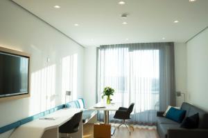 ein Wohnzimmer mit einem Tisch, einem Sofa und einem Fenster in der Unterkunft Seven Hotel + Boardinghouse in Herzogenaurach
