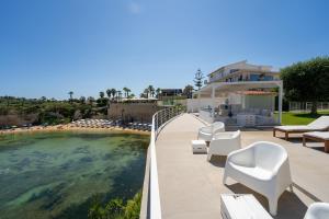 a patio with white chairs and a swimming pool at Buona Onda in Siracusa