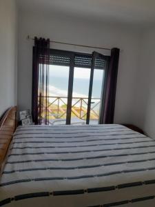 um quarto com uma cama e uma grande janela em Mar & Praia - Apartamento Pedra Ouro em Pedra Do Ouro