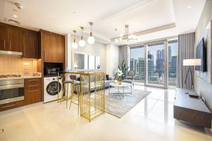 a kitchen with wooden cabinets and a living room at Cozy 1Bed Connected to DubaiMall BurjKhalifa 5min in Dubai