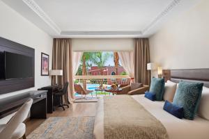 ein Schlafzimmer mit einem großen Bett und ein Wohnzimmer in der Unterkunft Savoy Le Grand Hotel Marrakech in Marrakesch