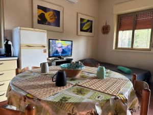 una cucina con tavolo e televisore in una stanza di Antonio's villa al mare con vista sull'Etna Vaccarizzo Catania a Catania