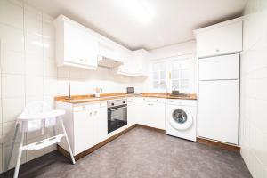 eine Küche mit weißen Schränken, einer Waschmaschine und einem Trockner in der Unterkunft Apartamento Carmiña in Puentedeume