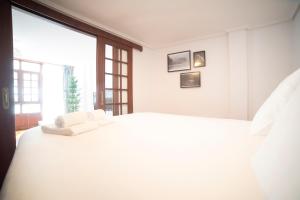 ein weißes Schlafzimmer mit einem großen weißen Bett und einem Fenster in der Unterkunft Apartamento Carmiña in Puentedeume