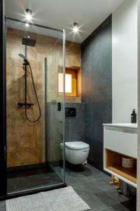 La salle de bains est pourvue d'une douche en verre et de toilettes. dans l'établissement DOMKI Sielsko Góra, à Gliczarów