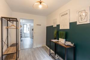 a room with a green accent wall and a table at Le 77 de Satie - City Centre Apartment Sleeps 3 in Honfleur