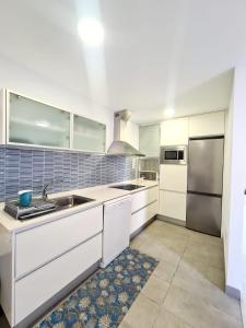 a kitchen with white cabinets and a stainless steel refrigerator at Vita Ideale in Arguineguín
