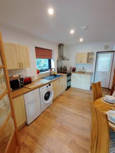 a kitchen with white appliances and a wooden floor at Bryn Mynach Annex in Barmouth