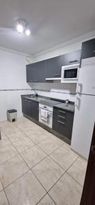 - une cuisine avec des armoires noires et un réfrigérateur blanc dans l'établissement Piso al lado de la playa, à Boiro