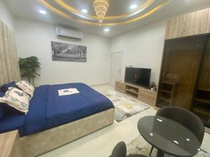 um quarto com uma cama, uma televisão e cadeiras em التوفيق للوحدات السكنية T1 em Al Ahsa