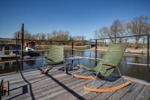 three chairs and a table on a dock near the water at Wunderschönes Hausboot AGATHE in Hamburg