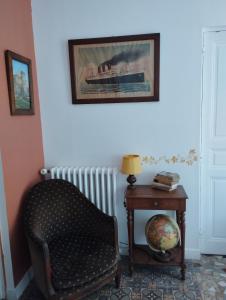 einen Stuhl und einen Tisch mit einem Bild an der Wand in der Unterkunft Le Voltaire in Souppes-sur-Loing