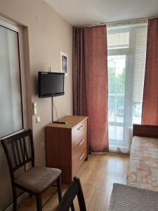 - une chambre avec un lit, une télévision et une chaise dans l'établissement Byala Silver Beach Apart, à Byala