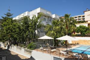 a hotel with a pool and tables and umbrellas at Skalidis Apartments in Tolo