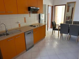 a kitchen with orange cabinets and a table with chairs at Villa M, App 4 - 6 persons direct on the seaside, 1st floor in Ljubač