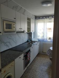 a kitchen with white cabinets and a sink and a microwave at Apartamento Vicsus in Ajo