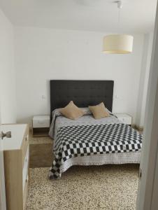 a bedroom with a bed with a black and white checkered blanket at Apartamento Vicsus in Ajo