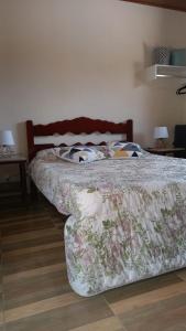 a bedroom with a bed with a floral bedspread at Chalés Mimar Lumiar Suítes individuais in Lumiar