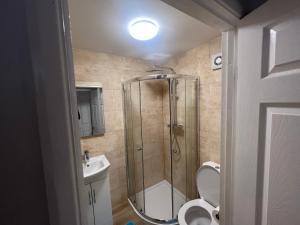 a bathroom with a shower with a toilet and a sink at Corby Guest House in Corby