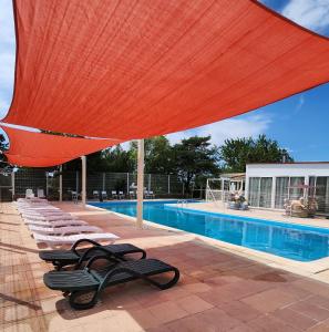 una piscina con sedie a sdraio e un grande ombrellone rosso di Mobil-home gorges du verdon lac de sainte croix camping poney a Sainte-Croix-de-Verdon