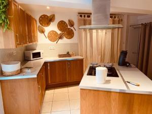 una cucina con armadi in legno e piano di lavoro bianco di Magnifique appartement bohème / sauna / balneo a Valros