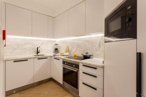 eine weiße Küche mit einer Spüle und einer Mikrowelle in der Unterkunft JOIVY Cosy apt in Parede near the beach in Parede