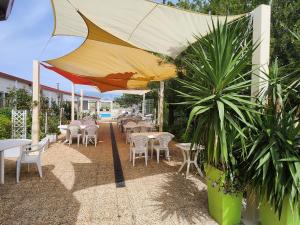 un patio con tavoli, sedie e ombrellone di Mobil-home gorges du verdon lac de sainte croix camping poney a Sainte-Croix-de-Verdon