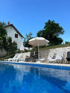um grupo de cadeiras e um guarda-sol junto a uma piscina em Vir em Nikšić