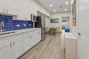 a kitchen with white cabinets and a blue tile wall at Seaport Suites in Wildwood