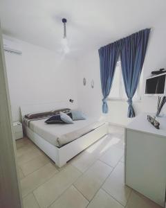 - une chambre blanche dotée d'un lit avec des rideaux bleus dans l'établissement STILL HOUSE, à San Nicola Arcella