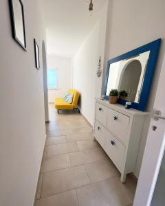 un couloir avec une commode avec un miroir et une chaise jaune dans l'établissement STILL HOUSE, à San Nicola Arcella
