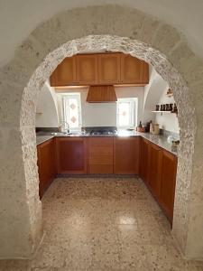 アルベロベッロにあるアグリ アンティーキ トゥルッリ B ＆ B イン マッセリアの石造りのアーチ道付きキッチン