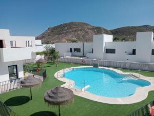 una gran piscina con sombrillas frente a un edificio en Apartamentos Cala San Pedro, en Las Negras