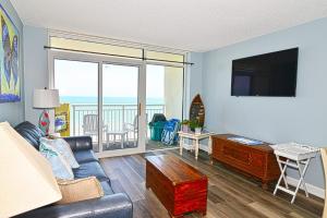 ein Wohnzimmer mit einem Sofa, einem TV und einem Balkon in der Unterkunft Oceanfront with Lazy River and Huge Pool Oasis in Myrtle Beach
