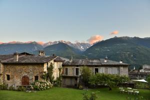 a large stone house with mountains in the background at Piano nobile al Roseto del Drago in San Bernardo