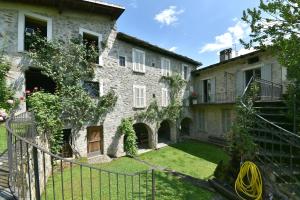 une ancienne maison en pierre avec un portail et une cour dans l'établissement Piano nobile al Roseto del Drago, à San Bernardo