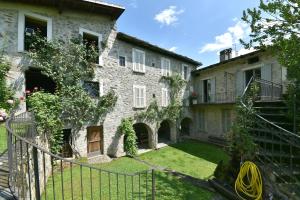 an old stone house with a gate and a yard at Piano nobile al Roseto del Drago in San Bernardo