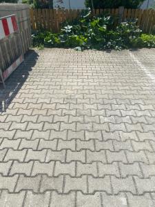 a brick driveway with a fence in the background at Apartment S&A in Holzkirchen