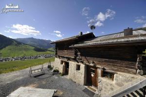 un antiguo edificio de madera al lado de una montaña en Chalet Heaven Mottolino en Livigno