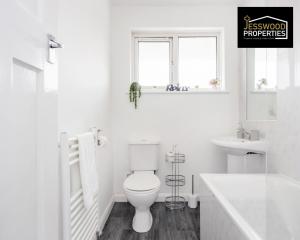 a white bathroom with a toilet and a sink at Modern Three Bedroom Contractor House With Free Parking Near M1 Luton Airport By Jesswood Properties Short Lets in Luton