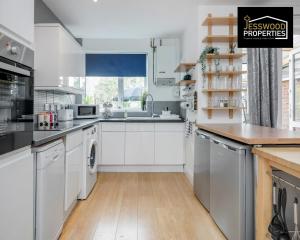 a kitchen with white cabinets and a wooden floor at Modern Three Bedroom Contractor House With Free Parking Near M1 Luton Airport By Jesswood Properties Short Lets in Luton