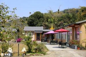 una casa con tavoli e ombrelloni di fronte di Xiangcun Homestay a Gukeng