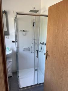 een douche met een glazen deur in de badkamer bij Hubertushaus in Burgen