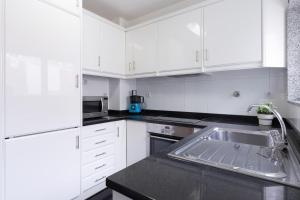 - une cuisine blanche avec un évier et des placards blancs dans l'établissement Deluxe Modern Flat w/ Balcony by Host Wise, à Porto
