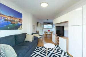 a living room with a blue couch and a kitchen at Deluxe Modern Flat w/ Balcony by Host Wise in Porto