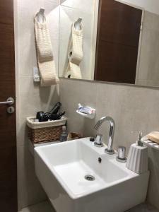 y baño con lavabo blanco y espejo. en Departamento del Parque en San Miguel de Tucumán